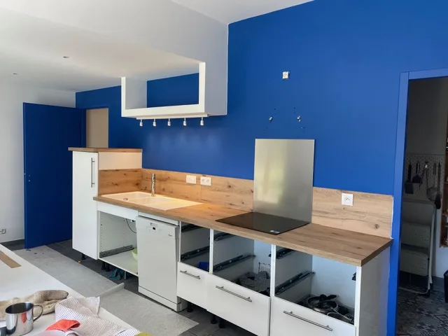 Cuisine rénovée par ECE travaux : mur bleu, plan de travail en bois