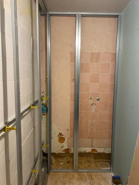 Salle d'eau avant travaux : ossature métallique devant l'ancienne faïence rose