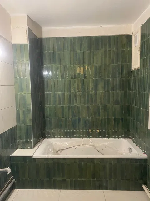 La même salle de bains après travaux, faïence verte autour de la baignoire